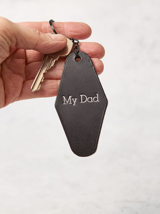 Black leather hotel inspired keychain with My Dad stamped on it in silver text.