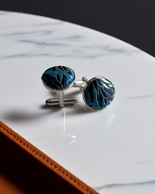 Blue patterned cufflinks on a marble surface