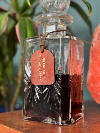 Hand Dyed Leather Bottle Tag attached around a glass decanter filled with sherry.