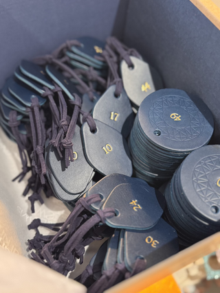 Leather navy cloakroom tags for the Savoy in London in two different shapes with gold numbers on them