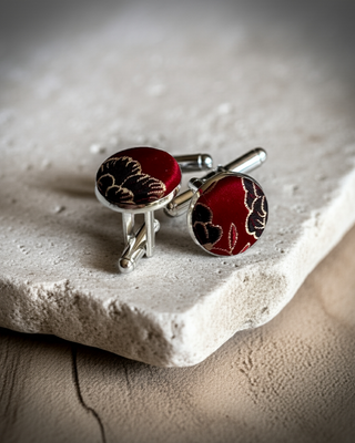 Red and black floral cufflinks on a textured stone surface