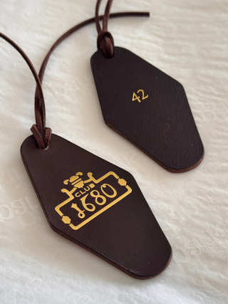 Two brown leather tags with gold embossed text on a white background