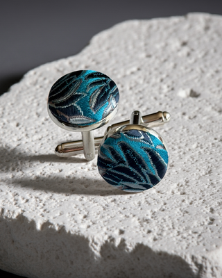 Blue and silver cufflinks on a textured white surface