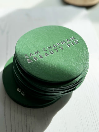 Green Beauty Pie Leather Coaster with silver lettering.