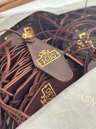 Brown leather tag with yellow text on a product packaging