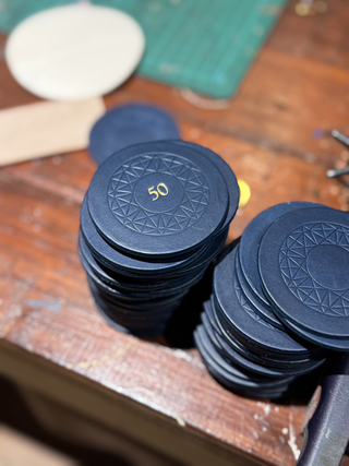 Navy blue leather cloakroom label for the Savoy in london with gold 50 stamped in the middle.