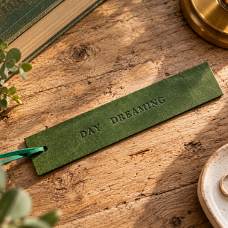Green leather bookmark on rustic wooden bed side table.