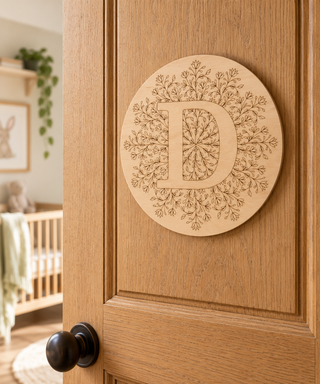 Laser engraved monogram wooden disc on a wooden door of a child's bedroom.