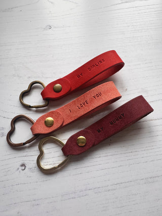 3 red leather keychains with heart-shaped ring on a white background