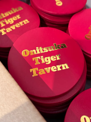 Red coasters with 'Onitsuka Tiger Tavern' text in gold.