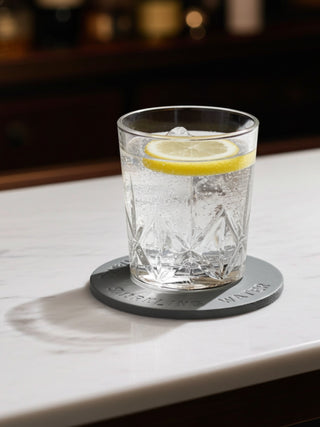 Glass of water with lemon slice on a grey leather coaster on a bar counter