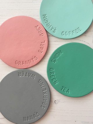 Four round colourful coasters with text on a light wooden surface