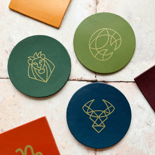 Zodiac leather coasters. Zodiac symbol on a round or square hand painted leather coaster. Available in navy, olive, avocado, raspberry, yellow and terracotta. The symbol is applied on in gold.